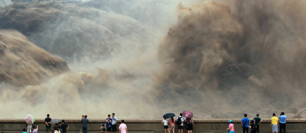 This picture taken on July 6, 2012 shows visitors gathering to watch giant gushes of water being released from the Xiaolangdi dam to clear up the sediment-laden Yellow river and to prevent localized flooding, in Jiyuan, central China's Henan province. China is hit by big downpours every summer often causing fatalities as seen in 2010, which saw the nation's worst flooding in a decade leaving more than 4,300 people dead or missing. CHINA OUT AFP PHOTO (Photo credit should read STR/AFP/GettyImages)