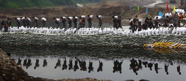 This picture taken on July 26, 2012 shows rescuers piling sandbags along a riverbank to prevent another flooding in the worst-hit area of Fangshan, on Beijing's mountainous southwestern outskirts, as distraught residents reported cars being swept away and said many people were still missing. The death toll from the worst rains to hit Beijing in more than 60 years has risen to 77, China's official Xinhua news agency said, more than doubling previous figures. CHINA OUT AFP PHOTO (Photo credit should read STR/AFP/GettyImages)