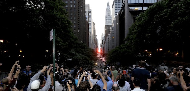 Photographers aim their cameras as the sun sets through the buildings on 42nd Street in New York's Manhattan borough during a phenomenon known as Manhattanhenge, Wednesday, July 11, 2012. Manhattanhenge, sometimes referred to as the Manhattan Solstice, happens when the setting sun aligns with the east-to-west streets of the main street grid. The term references Stonehenge, at which the sun aligns with the stones on the solstices in England. (AP Photo/Julio Cortez)
