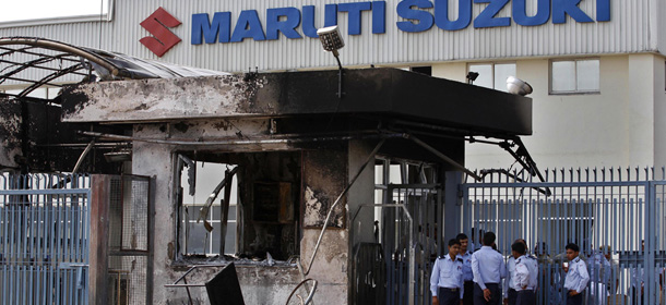 Security guards stand near a burnt down reception block of Maruti Suzuki factory in Manesar, near New Delhi, India, Thursday, July 19, 2012. According to news reports, one person died and at least 40 people were injured in Wednesday's labor unrest at the Manesar facility of India's largest passenger car maker. (AP Photo/ Saurabh Das)