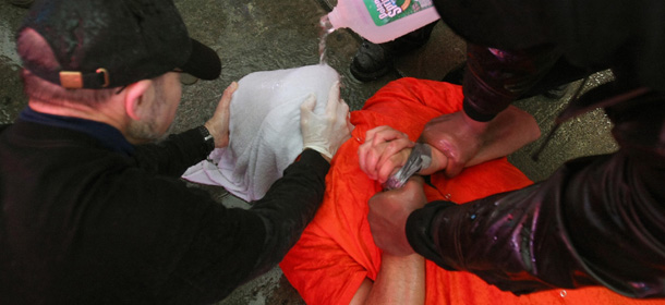 Demonstrators from the group "World Can't Wait" hold a mock waterboarding torture of a prisioner in Times Square 11 January 2008 to mark the sixth year anniversary of when the United States opened the camps at Guantanamo. Waterboarding is a form of torture that consists of immobilizing a person on his or her back, with the head inclined downward, and pouring water over the face and into the breathing passages. AFP PHOTO / Timothy A. CLARY (Photo credit should read TIMOTHY A. CLARY/AFP/Getty Images)