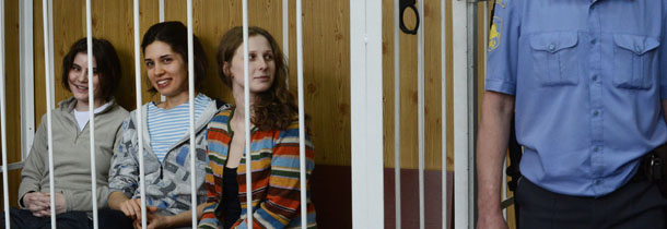 Members of the all-girl punk band "Pussy Riot" Nadezhda Tolokonnikova (C), Maria Alyokhina (R) and Yekaterina Samutsevich (L), sit behind bars during a court hearing in Moscow on July 20, 2012. Three members of the all-woman punk band "Pussy Riot" were detained, on charche of hooliganism for barging into a Moscow church and singing a "punk prayer" calling for the ouster of President Vladimir Putin on February 21, 2012". The trio, who face up to seven years in jail, have been held in pre-trial detention since March after the incident in February, and their harsh treatment has become a new rallying cause for the anti-Putin opposition. AFP PHOTO / NATALIA KOLESNIKOVA (Photo credit should read NATALIA KOLESNIKOVA/AFP/GettyImages)