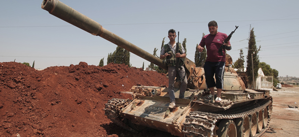 Syrian rebel fighters stand on top of a government tank captured two days earlier at a checkpoint in the village of Anadan, about five kilometres (3.8 miles) northwest of Aleppo, on August 01, 2012. The strategic checkpoint of Anadan secures the rebel fighters free movement between the northern city of Aleppo and Turkey, a Free Syrian Army commander and an AFP journalist said. AFP PHOTO/AHMAD GHARABLI (Photo credit should read AHMAD GHARABLI/AFP/GettyImages)