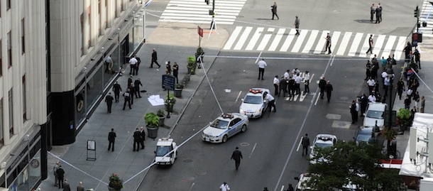 Police surround a sheet covered body, lower left, on a Fifth Avenue sidewalk as they investigate a multiple shooting outside the Empire State Building, Friday, Aug. 24, 2012, in New York. At least four people were shot on Friday morning and the gunman was dead, New York City officials said. A witness said the gunman was firing indiscriminately. Police said as many as 10 people were injured, but it is unclear how many were hit by bullets. A law enforcement official said the shooting was related to a workplace dispute. The official spoke on condition of anonymity because the investigation was ongoing. (AP Photo/ Louis Lanzano)