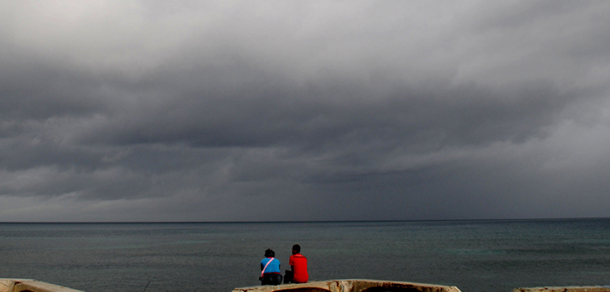 A couple sit on a bench under cloudy skies along the shore of Santo Domingo, Dominican Republic, Thursday, Aug. 23, 2012. Tropical Storm Isaac churned toward the Dominican Republic and Haiti on Thursday, threatening to strengthen into a hurricane. (AP Photo/Manuel Diaz)