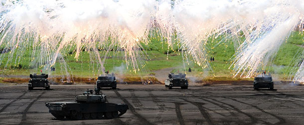 Japanese Ground Self-Defense Forces tanks move amongst an umbrella of barrage during an annual live fire exercise at the Higashi-Fuji firing range in Gotemba, at the foot of Mt. Fuji in Shizuoka prefecture on August 21, 2012. The annual drill involves some 2,400 personnel, 80 tanks and armoured vehicles and 30 aircraft and helicopters. AFP PHOTO / Yoshikazu TSUNO (Photo credit should read YOSHIKAZU TSUNO/AFP/GettyImages)