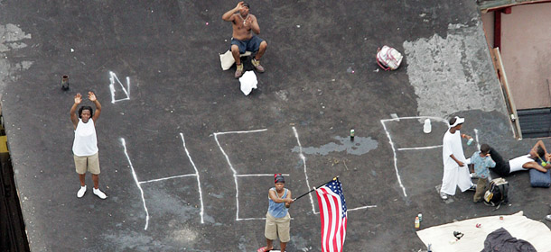 New Orleans residents wait to be rescued from the floodwaters of Hurricane Katrina 01 September, 2005. Stretched relief services flailed away Thursday at a vast refugee crisis developing, unbelievably, within US borders, following a mass human exodus from Hurricane Katrina. Scenes emerged of desperation, deprivation and human agony, which Americans are used to seeing only on their television screens from the world's hotspots. "It's the Third World," said one medical professional, who requested anonymity, in order not damage his hopes of being sent into blacked out hospitals in New Orleans, after repeated requests. AFP PHOTO/POOL/DAVID J. PHILLIP/GETTY OUT (Photo credit should read DAVID J. PHILLIP/AFP/Getty Images)