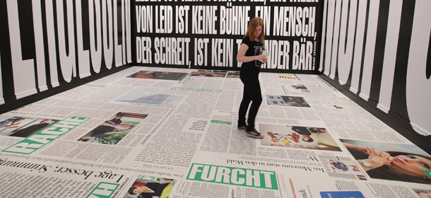 BERLIN, GERMANY - MARCH 26: A young woman walks through an installation by artist Barbara Kruger at the exhibition "ARTandPRESS" at Martin Gropius Bau on March 26, 2012 in Berlin, Germany. The exhibition shows works by artists who have interpreted the medium of newspapers and is open from March 23 to June 24. (Photo by Sean Gallup/Getty Images)