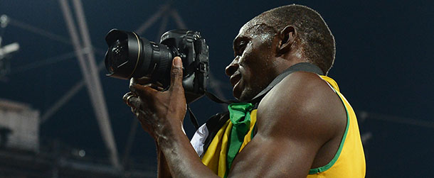 Jamaica's Usain Bolt takes pictures with a camera of a photographer after winning gold in the men's 200m final at the athletics event during the London 2012 Olympic Games on August 9, 2012 in London. Usain Bolt retained his 200m title on Thursday to become the first man to achieve the sprint double at consecutive Olympics. AFP PHOTO / FRANCISCO LEONG (Photo credit should read FRANCISCO LEONG/AFP/GettyImages)