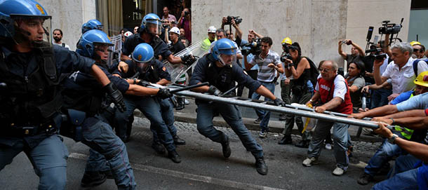 Employees of the world's leading producer of primary aluminum Alcoa, clash with police during a demonstration outside the industry ministry in Rome on September 10, 2012, as Prime Minister Mario Monti's government holds talks to find a solution. The demonstrators protest against the closing of Portovesme and Fusina melting plants on the Italian island of Sardinia which employ about 2,000 people. Alcoa blamed "factors beyond our control" including "the economic situation and the burdens imposed by the European regulatory system" for the shutdown of the factory, which it said would take several weeks. AFP PHOTO / ANDREAS SOLARO (Photo credit should read ANDREAS SOLARO/AFP/GettyImages)