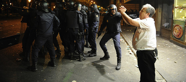Restaurant owner Alberto Casillas (R) shouts behind riot policemen during a demonstration organized by Spain&#8217;s &#8220;indignant&#8221; protesters to decry an economic crisis they say has &#8220;kidnapped&#8221; democracy, on September 25, 2012 in Madrid. Spanish riot police fired rubber bullets and baton-charged protesters as thousands rallied near parliament in Madrid in anger at the government&#8217;s handling of the economic crisis. AFP PHOTO / DOMINIQUE FAGET (Photo credit should read DOMINIQUE FAGET/AFP/GettyImages)
