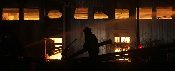 A fireman tries to extinguish a fire which broke out in a factory on Tuesday, Sept. 11, 2012 in Karachi, Pakistan. Factory fires in two of Pakistan's major cities killed 39 people and injured dozens more on Tuesday, including some who had to break through barred windows and leap to the ground to escape the flames. (AP Photo/Shakil Adil)