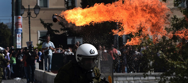 Firebombs explode in front of riot police on September 26, 2012 in Athens during clashes with demonstrators at a 24-hours general strike. Police in Athens clashed with hooded youths throwing firebombs on the sidelines of a large demonstration against a new round of austerity cuts. AFP PHOTO / ARIS MESSINIS (Photo credit should read ARIS MESSINIS/AFP/GettyImages)
