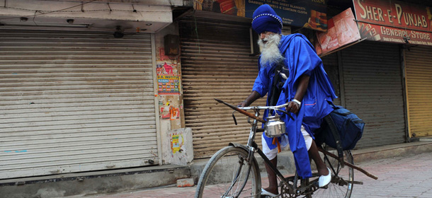 An Indian Sikh warrior cycles passed closed shops during a nationwide strike in Amritsar on September 20, 2012. Opposition parties and trade unions called for shopkeepers, traders and labourers in India to block railway lines and close markets to protest against reforms, designed by Prime Minister Manmohan Singh, to revive India&#8217;s slowing economy allowing in foreign retail giants such as Walmart and Tesco. AFP PHOTO/ NARINDER NANU (Photo credit should read NARINDER NANU/AFP/GettyImages)
