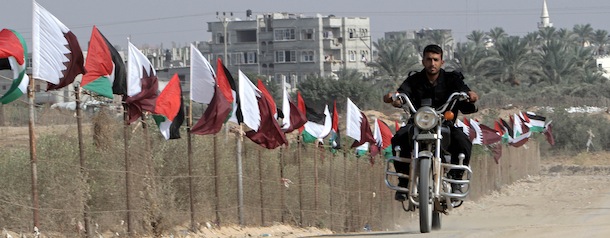 A member of the Palestinian Hamas security forces rides a motorcycle past Palestinian and Qatari flags displayed along the construction site of a residential project funded by Qatar in Khan Yunis in the southern Gaza Strip on October 22, 2012. The Qatari emir will visit Gaza on October 23 in the first such visit by an Arab leader since Hamas took over in 2007, sources close to the ruling Islamist movement said. AFP PHOTO/SAID KHATIB (Photo credit should read SAID KHATIB/AFP/Getty Images)
