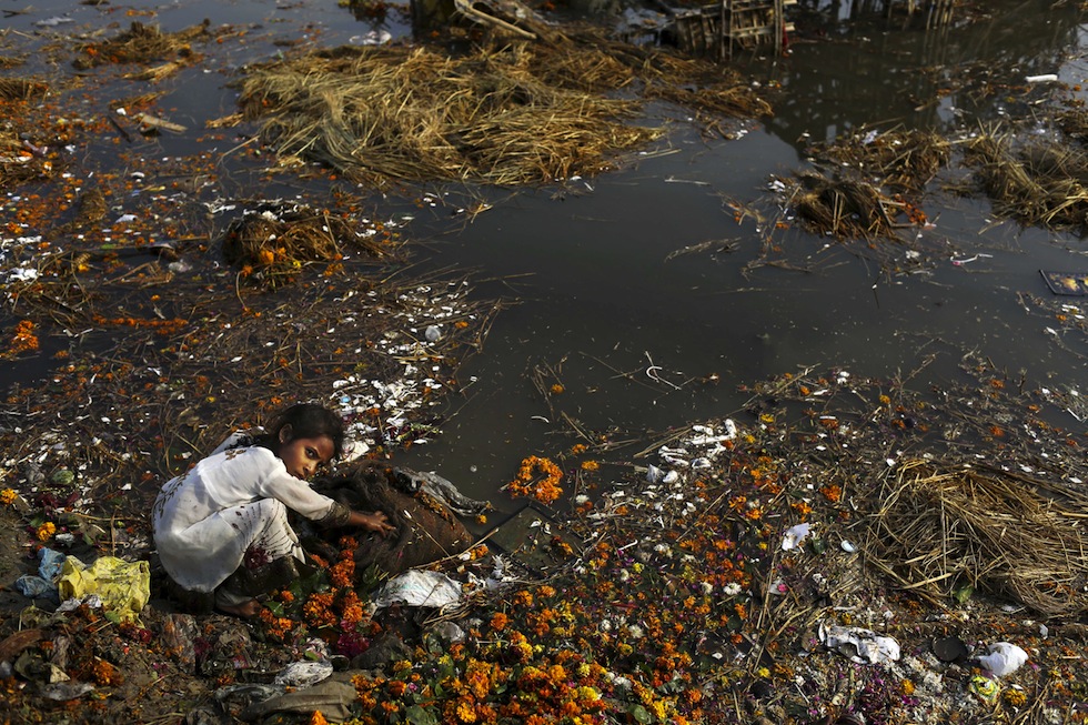 Una ragazza indiana tra i resti degli idoli immersi dai devoti indiani nel fiume Yamuna. Nuova Dehli, India, 25 ottobre 2012. (AP Photo/Kevin Frayer)
