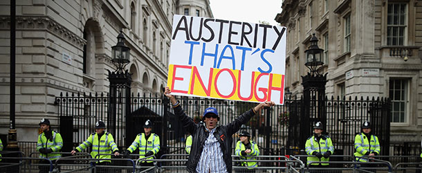 LONDON, UNITED KINGDOM &#8211; OCTOBER 20: A man holds up a banner reading &#8216;Austerity &#8211; That&#8217;s Enough&#8217; outside outside Number 10 Downing Street during a TUC march in protest against the government&#8217;s austerity measures on October 20, 2012 in London, England. Thousands of people are taking part in the Trades Union Congress (TUC) organised anti-cuts march that ends with a rally in Hyde Park, where Labour leader Ed Miliband is scheduled to address the demonstrators. (Photo by Dan Kitwood/Getty Images)
