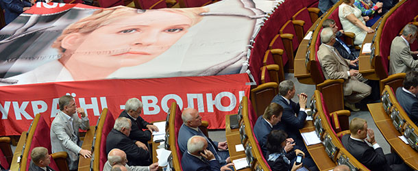 Ukrainian deputies sit next to a giant poster of jailed opposition leader Yulia Tymoshenko on September 4, 2012 during the opening of the last parliament session before the October 28 general elections in Kiev. In an interview published on September 3, Tymoshenko urged European powers to help free her country from its &#8220;dictator&#8221; President Viktor Yanukovych. AFP PHOTO / SERGEI SUPINSKY (Photo credit should read SERGEI SUPINSKY/AFP/GettyImages)
