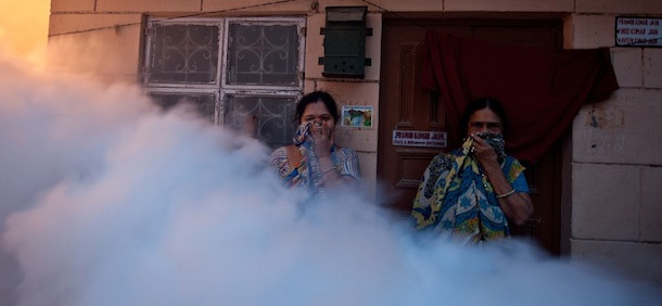 Residents cover their faces to avoid smoke as municipal health workers fumigate a neighbourhood against mosquitoes in New Delhi on November 7, 2012. Dengue continued to spread in the Indian capital with 39 fresh cases being reported November 7, taking the toll of people detected with the mosquito-borne disease this season to 1,288, according to Press Trust of India (PTI). AFP PHOTO/MANAN VATSYAYANA (Photo credit should read MANAN VATSYAYANA/AFP/Getty Images)
