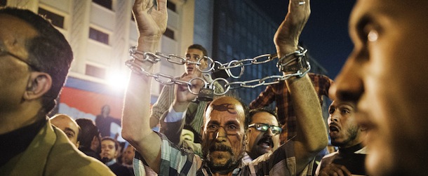 An Egyptian man with his wrists bound by a chain joins thousands of Egyptian protesters as they rally and shout slogans against the Egyptian Security forces during clashes with the police on November 19, 2012 in Cairo, Egypt. Protesters in Egypt&#8217;s capital clashed with police during a protest to mark a year since a five-day long street battle with security forces in which dozens of protesters were killed, witnesses said. AFP PHOTO/GIANLUIGI GUERCIA (Photo credit should read GIANLUIGI GUERCIA/AFP/Getty Images)
