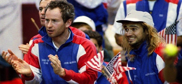 FORT WORTH, TX &#8211; DECEMBER 4: U.S. tennis players John McEnroe (L) and Andre Agassi cheer for teammate Jim Courier as he plays Switzerland&#8217;s Marc Rosset in the second match of the Davis Cup finals 04 December 1992. Rosset defeated Courier 6-3, 7-6, 3-6, 6-4, 6-4. (Photo credit should read TIM ROBERTS/AFP/Getty Images)
