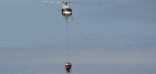 In this Nov. 11, 2012 photo released by Galapagos National Park, a helicopter tests carrying a container that will hold poisonous bait to kill rats on the Galapagos Islands, over Baltra Island. To preserve the unique birds, reptiles and native plants that make the Galapagos Islands such an ecological treasure, authorities will start on Wednesday, Nov. 14, 2012 phase II of a mass kill-off of black and Norway rats, an invasive species introduced to the Pacific Ocean islands by whalers and buccaneers beginning in the 17 century. (AP Photo/Galapagos National Park)
