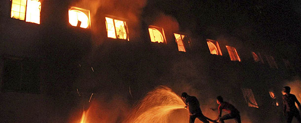 Bangladeshis and firefighters battle a fire at a garment factory in the Savar neighborhood in Dhaka, Bangladesh, late Saturday, Nov. 24, 2012. An official said firefighters have recovered more than 100 bodies after a fire raced through the multi-story garment factory just outside Bangladesh&#8217;s capital. (AP Photo/Polash Khan)
