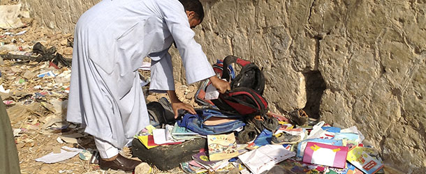 RETRANSMISSION FOR ALTERNATE CROP &#8212; An Egyptian looks through books and school bags that were strewn along the tracks at the scene where a speeding train crashed into a bus carrying children to their kindergarten, killing at least 47, officials said, near Assiut in southern Egypt, Saturday, Nov. 17, 2012. The bus was carrying more than 50 children between 4 and 6 years old when it was hit by a train near al-Mandara village in Manfaloot district in the province of Assiut, a security official said, adding that it appears that the railroad crossing was not closed as the train sped toward it. (AP Photo/Mamdouh Thabet)
