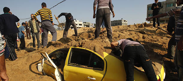 Palestinian men try to pull out civilians blocked in a car after an Israeli air raid on the area of Twaam in the northern Gaza town of Beit Lahia on November 15, 2012. Israeli air strikes have killed more than ten Gazans, including top Hamas commander Ahmed Jaabari, as three Israelis die when a rocket strikes a house, in the latest flareup of tit-for-tat fighting. AFP PHOTO / MOHAMMED ABED (Photo credit should read MOHAMMED ABED/AFP/Getty Images)
