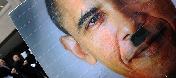 People walk past a poster depicting US President Barack Obama as Adolf Hitler during a demonstration by a group from LaRouche Political Action Committee near the White House in Washington, DC, on January 25, 2011 ahead of Obama&#8217;s State of Union speech. A resurgent Obama seeks to define the year&#8217;s political battles in his State of the Union address, amid a developing tussle over spending with empowered, but restive Republicans. Obama will speak from a unique national pulpit before a television audience of millions when he is greeted by standing ovations and political theatrics in the House of Representatives, for the annual speech at 9 pm (0200 GMT). AFP PHOTO/Jewel Samad (Photo credit should read JEWEL SAMAD/AFP/Getty Images)
