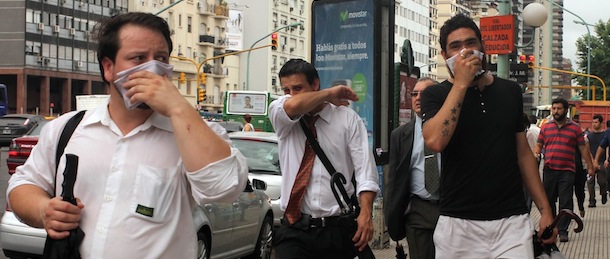 People cover their mouths and nostrils as they walk along an avenue on December 6, 2012 in Buenos Aires. Several buildings in downtown Buenos Aires were evacuated when a fire in a container loaded with a chemical substance near the port area released a toxic cloud with a strong stench, the Civil Defense said. AFP PHOTO/STR (Photo credit should read STR/AFP/Getty Images)
