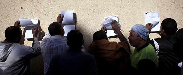 Egyptian voters check voter lists outside a polling station during the second round of a referendum on a disputed constitution drafted by Islamist supporters of president Mohammed Morsi, in Giza, Egypt, Saturday, Dec. 22, 2012. (AP Photo/Nasser Nasser)
