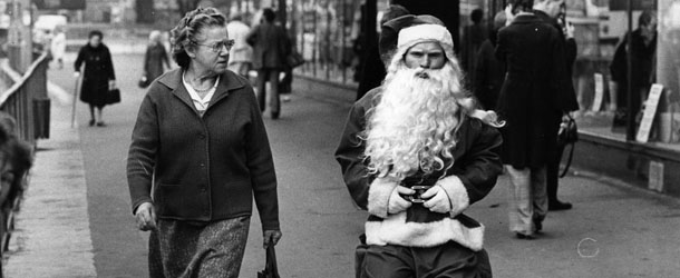 1975: A woman casts a sceptical glance at a rather surly looking man dressed as Santa in a busy shopping street. (Photo by Evening Standard/Getty Images)
