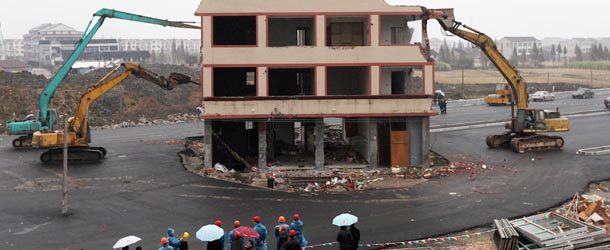 CORRECTION
This picture taken on December 1, 2012 shows a couple of excavators tearing down the five-storey apartment building in the middle of a newly-built road in Wenling, in eastern China&#8217;s Zhejiang province. Local authorities said that the house was bulldozed on December 1 after its owners, duck farmer Luo Baogen and his wife, agreed to accept compensation of 40,000 USD. The phenomenon is called a &#8220;nail house&#8221; in China, as such buildings stick out and are difficult to remove, like a stubborn nail. CHINA OUT AFP PHOTO (Photo credit should read STR/AFP/Getty Images)
