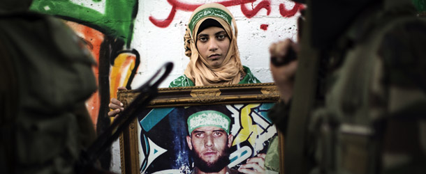A Palestinian woman holds the portrait of a killed relative belonging to the Ezzedine al-Qassam brigade during a march by Hamas armed wing in Beit Hanun on December 6, 2012. The Hamas government confirmed that the Islamist movement&#8217;s exiled politburo chief Khaled Meshaal was due in the Gaza Strip to celebrate its 25th anniversary. AFP PHOTO/MARCO LONGARI (Photo credit should read MARCO LONGARI/AFP/Getty Images)
