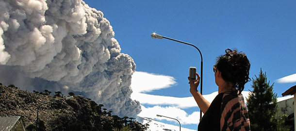 A woman takes a picture with her mobile phone from Caviahue, Neuquen province, Argentina, some 1500 km southwest of Buenos Aires, of the Copahue volcano spewing ashes on December 22, 2012. The authorities of Chile and Argentina issued yellow alerts due to the eruption of the Copahue volcano, placed in the border between both countries. AFP PHOTO / Antonio Huglich (Photo credit should read Antonio Huglich/AFP/Getty Images)
