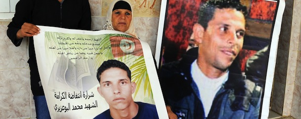 (FIELS) A picture taken on November 15, 2011 shows the mother of Mohamed Bouazizi, the fruitseller whose self-immolation sparked the revolution that ousted a dictator in Yunisia and ignited the Arab Spring, Manoubia Bouazizi (C) and her daughters Leila (R) and Basma (L) posing posing with posters of Mohamed, in Tunis. Slogan reads: "The spark of the revolution -- martyr Mohamed Bouazizi." Bouazizi, a 26-year-old university graduate who has only been able to find work as a fruitseller, sets himself alight on December 17, 2010 to protest harassment and unemployment. Two days later rioting breaks out. Bouazizi dies from his burns on January 5, 2011. During the unrest some 300 people are killed, according to the UN, and hundreds are arrested. AFP PHOTO/ FETHI BELAID (Photo credit should read FETHI BELAID/AFP/Getty Images)