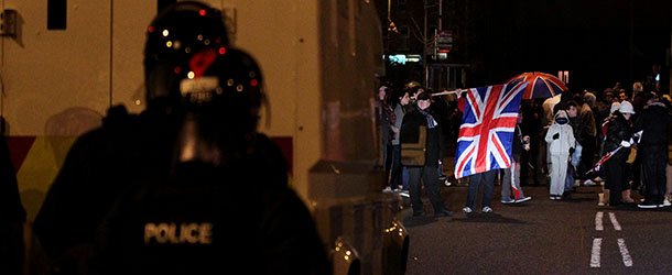 Police stand guard as protesters wave the Union flag during clashes in Belfast, Northern Ireland, on January 4, 2013. Tensions have risen in the British province since councillors voted on December 3, 2012 to limit the number of days the Union flag can fly over the City Hall to 17, outraging loyalists who believe Northern Ireland should retain strong links to Britain. AFP PHOTO/ PETER MUHLY (Photo credit should read PETER MUHLY/AFP/Getty Images)
