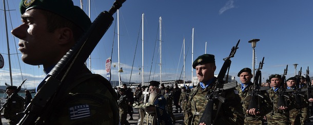 A priest holds a cross flanked by soldiers as they arrive to bless the waters during a ceremony marking Epiphany Day in the city of Voloson January 6, 2013. 
AFP PHOTO / LOUISA GOULIAMAKI (Photo credit should read LOUISA GOULIAMAKI/AFP/Getty Images)