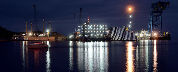 A worker stands on a platform in front of the Costa Concordia cruise ship laying aground near the port on January 8, 2013 on the Italian island of Isola del Giglio. Works are going ahead after almost a year ago, on January 13, 2012, the giant Italian cruise ship Costa Concordia ran aground near a Tuscan island and pitched leaving 32 people dead. AFP PHOTO / FILIPPO MONTEFORTE (Photo credit should read FILIPPO MONTEFORTE/AFP/Getty Images)