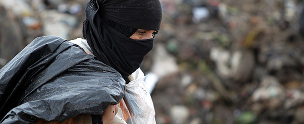 An Iraqi woman searches for plastic bottles in a garbage dump on the outskirts of Baghdad's impoverished district of Sadr City, January 30, 2013. Around a quarter of Iraq's population are estimated by the country's Planning Ministry to live in poverty, and many survive in vast refuge dumps where they search for subsistence, either via using disposed goods or finding items that can be handed to recycling plants for money. AFP PHOTO/AHMAD AL-RUBAYE (Photo credit should read AHMAD AL-RUBAYE/AFP/Getty Images)