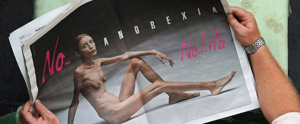 A man reads an Italian newspaper in Rome 24 September 2007, showing the new fashion brand Nolita advertising campaign against anorexia, realised by Oliviero Toscani. Toscani laid the subject bare, to show the reality of the sickness to all throught this naked body. The campaign is backed by Italy's Ministry for Health. (Photo credit should read ALBERTO PIZZOLI/AFP/Getty Images)