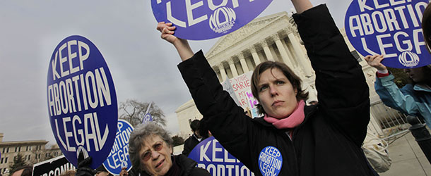 Abortion-rights activist and National Organization for Women (NOW) member Erin Matson, right, and others, holds up a signs as anti-abortion demonstrators march towards the Supreme Court in Washington, Friday, Jan. 22, 2010. (AP Photo/Pablo Martinez Monsivais)