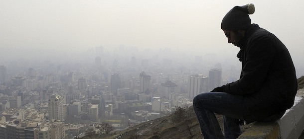 An Iranian man sits on a curb in the Tochal mountainous area overlooking the polluted skyline of the capital Tehran, Iran, Friday, Jan. 4, 2013. Government has ordered Tehran province schools, and government offices to close Saturday, Jan. 5, because of high air pollution in the province, Iran's state news agency IRNA reported Thursday Jan. 3. Such closure came last month because of dangerous air pollution levels. (AP Photo/Vahid Salemi)