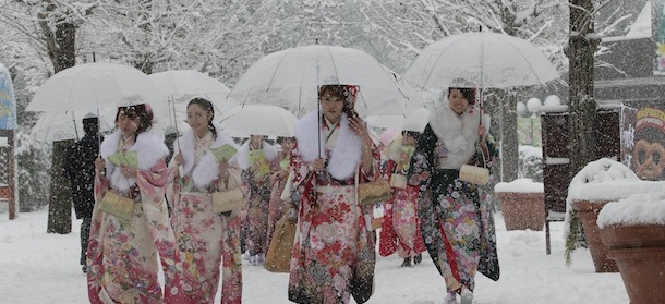 Dressed in Japanese kimonos, Japanese youths who have turned or will turn 20-year-old this year, the traditional age of adulthood in Japan, walk in the snow following a Coming of Age ceremony at an amusement park in Tokyo Monday, Jan. 14, 2013. (AP Photo/Shizuo Kambayashi)