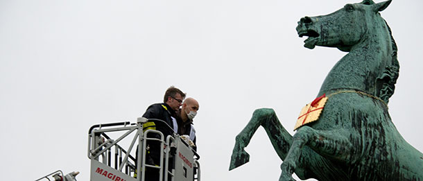 Forensic scientists take off a golden "Leibniz Keks" cookie, the logo of the German Bahlsen biscuit company, from a horse statue of the "Niedersachsenpferd", the heraldic animal of Lower Saxony, standing in front of the Leibniz university in Hanover, central Germany, on February 5, 2013. The Bahlsen company was blackmailed by unknown persons who had stolen the golden cookie in January 2013, demanding the company to deliver free cookies to children's hospitals in order to get the trademark sign back. After Bahlsen chairman Werner Bahlsen had promised to offer cookies to 52 social institutions, a golden cookie was found around the neck of the horse statue, but it's not yet clear if it's the original, 20 kg gold plated trade mark. AFP PHOTO / JOCHEN LUEBKE GERMANY OUT (Photo credit should read JOCHEN LUEBKE/AFP/Getty Images)