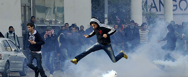 A Tunisian protester jumps amid smoke after police fired tear gas during a rallye outside the Interior ministry to protest after Tunisian opposition leader and outspoken government critic Chokri Belaid was shot dead with three bullets fired from close range, on February 6, 2013 in Tunis. The protesters, who massed on Habib Bourguiba Avenue, epicentre of the 2011 uprising that ousted ex-dictator Zine El Abidine Ben Ali, pelted the police with bottles and the police responded by firing tear gas, chasing the protesters and beating them with batons. AFP PHOTO / FETHI BELAID (Photo credit should read FETHI BELAID/AFP/Getty Images)