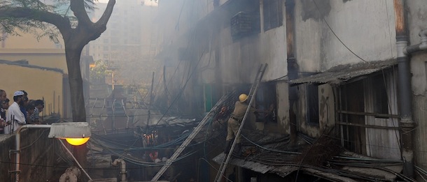Bystanders (bottom L) look on as Indian firefighters attempt to control a blaze in the Surya Sen market building in Kolkata on February 27, 2013. A fire swept through a six-storey building housing an illegal market in the eastern Indian city of Kolkata, killing 13 people who were unable to escape the inferno, local officials said. AFP PHOTO/Dibyangshu SARKAR (Photo credit should read DIBYANGSHU SARKAR/AFP/Getty Images)
