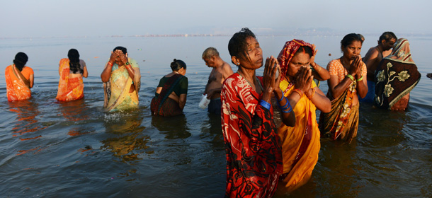 Indian devotees pray as they stand in the Sangam or confluence of the Yamuna, Ganges and mythical Saraswati rivers at the Kumbh Mela in Allahabad on February 10, 2013. Tens of millions of Hindus gathered Sunday for a holy bath in India's sacred river Ganges on the most auspicious day of the world's largest religious festival. Ash-smeared naked saints led the ritual bathing before dawn, which is said to cleanse pilgrims of their sins, with millions following them into the swirling river waters at the festival site in Allahabad in northern India. AFP PHOTO/ROBERTO SCHMIDT (Photo credit should read ROBERTO SCHMIDT/AFP/Getty Images)