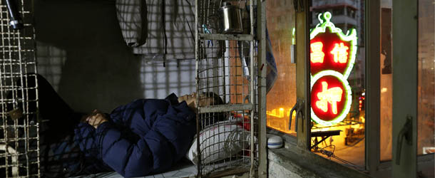 In this Jan. 25, 2013 photo, 62-year-old Cheng Man Wai lays in his cage, measuring 1.5 square meters (16 square feet), which he calls home, in Hong Kong. For many of the richest people in Hong Kong, one of Asia's wealthiest cities, home is a mansion with an expansive view from the heights of Victoria Peak. For some of the poorest, home is a metal cage. Some 100,000 people in the former British colony live in what's known as inadequate housing, according to the Society for Community Organization, a social welfare group. (AP Photo/Vincent Yu)